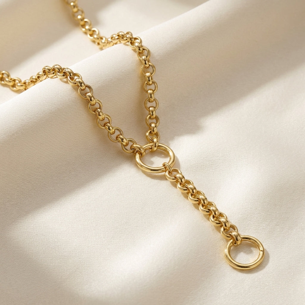 Styled flat lay of Italian 14K gold Rolo Chain with charm connector on textured fabric, emphasizing the slim links and detailed craftsmanship.