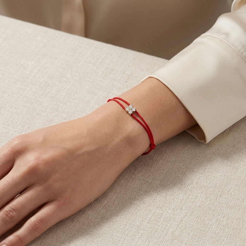 Studio close-up of a tiny 14K gold diamond red string bracelet highlighting micro-details and craftsmanship on textured background.