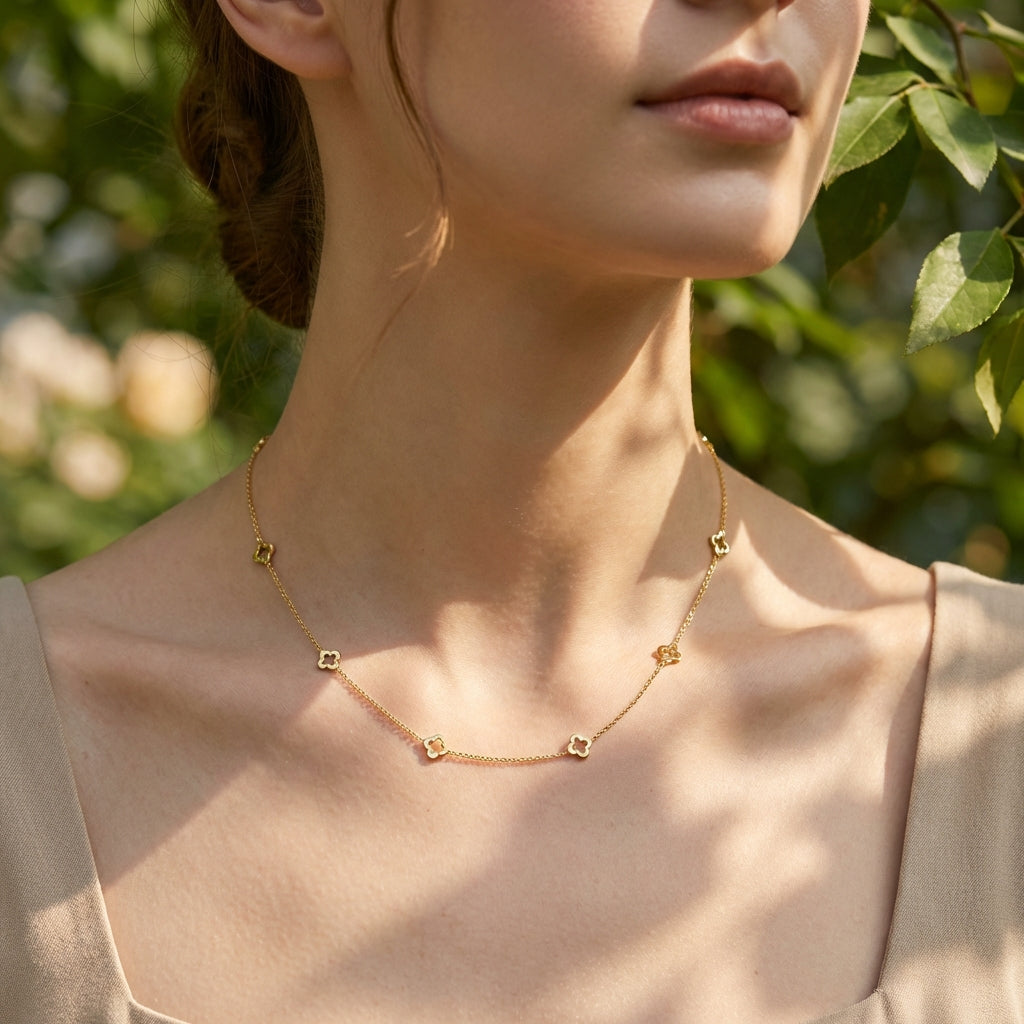 Elegant model with 14K gold open clover necklace resting below collarbone in natural outdoor setting, highlighting dainty design.